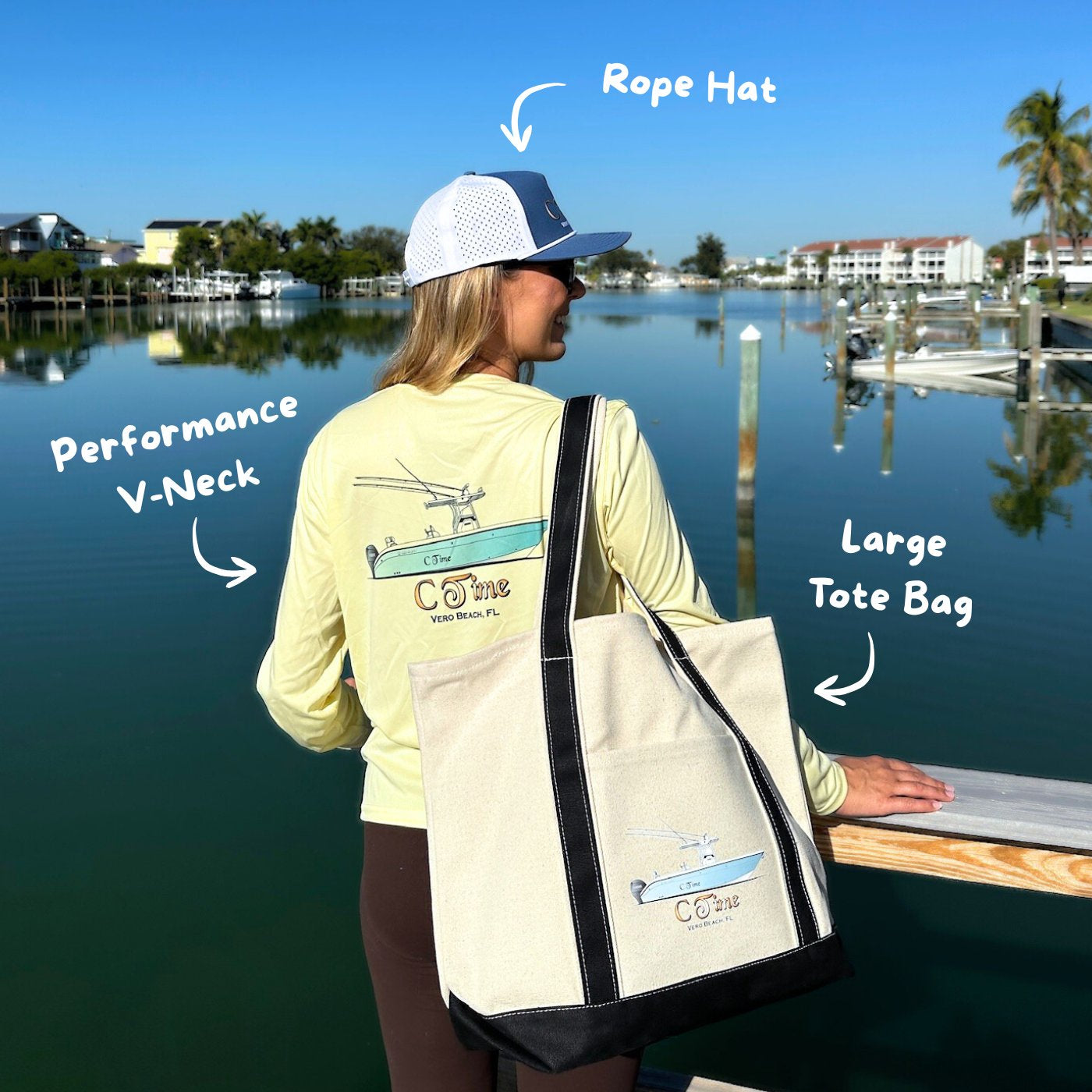 Person wearing custom boating apparel on performance V-neck shirt, rope hat, and large tote bag by a waterfront.
